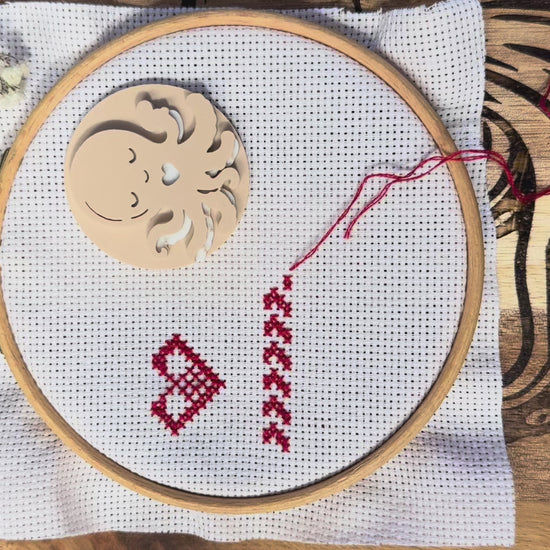 Sleeping Octopus magnetic needle minder in use, showing how the strong magnets attach securely through cross stitch or embroidery fabric and hold your needle safely in place while stitching.