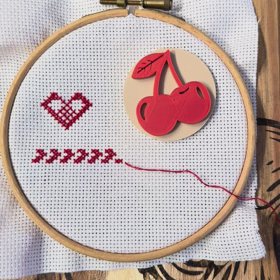 Cherry magnetic needle minder in use, showing how the strong magnets attach securely through cross stitch or embroidery fabric and hold your needle safely in place while stitching.
